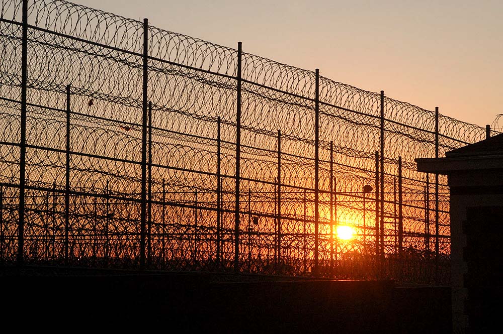 The sun sets behind the razor wire at the South Dakota State Penitentiary in Sioux Falls July 11, 2007, as the execution of Elijah Page, one of Briley Piper's codefendants, approached. (AP/Doug Dreyer)
