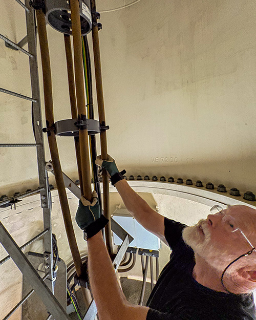 Benedictine Br. Joseph Byron climbs inside Portsmouth Abbey's wind turbine June 17, 2026. (NCR photo/Camillo Barone)