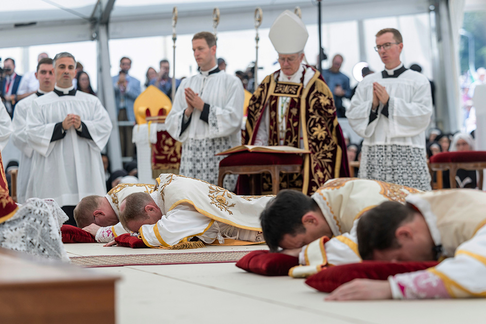 Four bishops lie on the floor as they are given episcopal consecration during a Mass in a tent set up outside the Society of St. Pius X seminary, in Econe, Switzerland, July 1, 2026. (Cyril Zingaro/Keystone via AP)