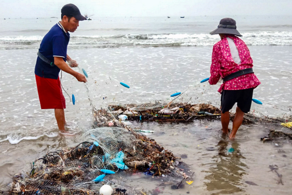 Workers remove trash from a clam-farming area in Vinh An, Vietnam, on June 17, 2026. Farmers say plastic waste and other flood-borne debris have contributed to declining harvests. (Joachim Pham)