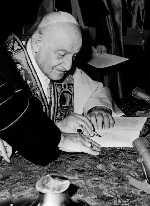 Pope John XXIII signs his encyclical "Peace on Earth" ("Pacem in Terris") at the Vatican in this 1963 file photo. (CNS)