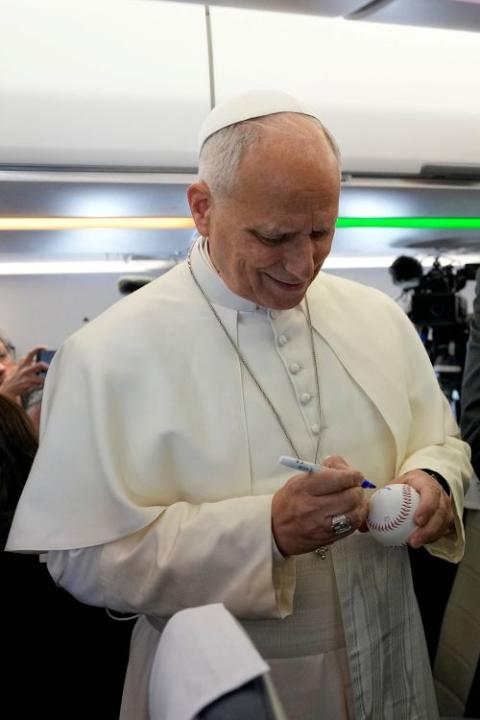 Pope Leo XIV signs a baseball presented by Spanish photojournalist Daniel Ibanez Gutierrez aboard the papal flight from Rome to Madrid June 6, 2026, the start of his apostolic journey to Spain. (OSV News/Reuters/Violeta Alessandra Tarantino)