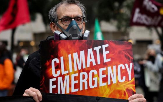 A climate activist wears a protective mask during a protest June 8, 2023, while smoke and haze caused by wildfires in Canada pass through New York City.  Pope Francis' 2015 encyclical "Laudato Si' " has spurred many Catholics to advocate for care of all God's creation.  (OSV News/Reuters/Amr Alfiky)