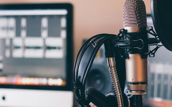 Headphones and a microphone are pictured in a studio setting. (Unsplash/Will Francis)
