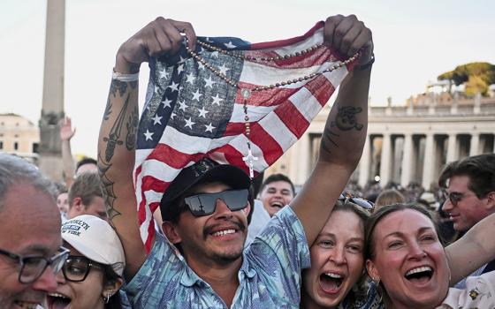 A man holding a rosary and U.S. flag reacts as Cardinal Robert Francis Prevost, who has chosen the papal name Leo XIV, appears on the central balcony of St. Peter's Basilica at the Vatican May 8, 2025, following his election during the conclave. (OSV News/Reuters/Dylan Martinez)