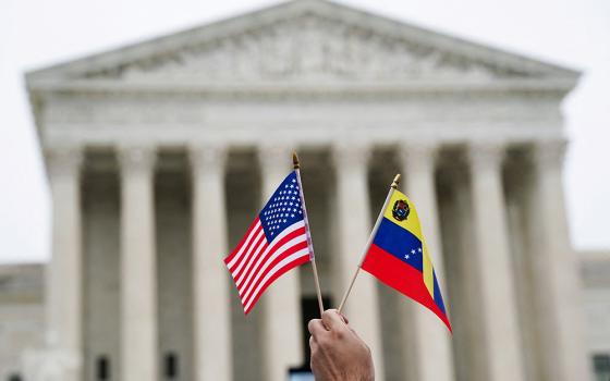 A person holds U.S. and Venezuelan flags as immigrants' rights activists and demonstrators attend a rally outside the U.S. Supreme Court in Washington April 29, 2026, as justices heard arguments on whether the administration of U.S. President Donald Trump can end the temporary protected status of Syrian and Haitian nationals. (OSV News/Reuters/Nathan Howard)