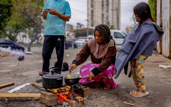 A woman burns wood on the street to cook a meal for her husband and their daughter outside their home in São Paulo Sept. 16, 2022. (OSV News/Reuters/Amanda Perobelli)
