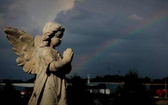 A rainbow appears in the distance near an angel grave marker following a thunderstorm at St. Patrick Catholic Cemetery in Neenah, Wisconsin. (CNS/The Compass/Brad Birkholz)