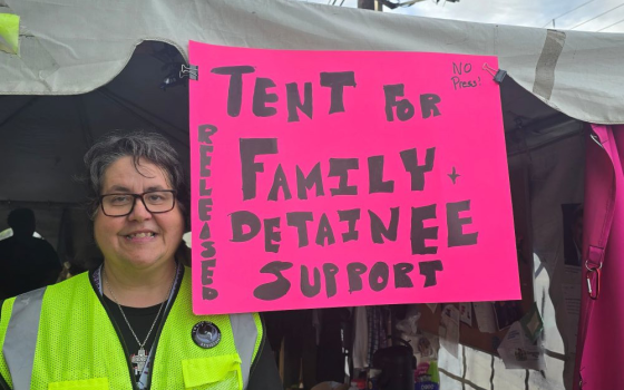 Sr. Susan Rose Francois of the Sisters of St. Joseph of Peace poses next to the sign outside the family and detainee support tent in front of Delaney Hall in Newark, New Jersey. (Courtesy of Eyes on ICE NJ/Joseph O'Leary)