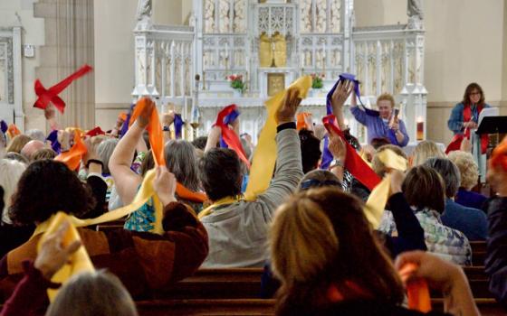 Attendees at the Women's Ordination Conference's 50th anniversary celebration wave multi-colored stoles Friday, May 22, 2026, in Detroit. (NCR photo/Dan Stockman)