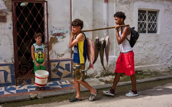 Youths carry freshly caught fish from the sea in Havana, Cuba, Monday, June 1, 2026. (RNS/AP/Ramon Espinosa)