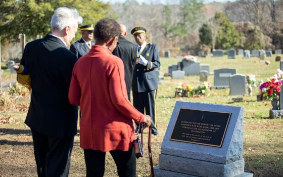 People pause to view a memorial marker to the unknown enslaved people buried at St. Peter Claver Parish's cemetery in St. Inigoes, Md., after Cardinal Wilton Gregory of Washington blessed the memorial Nov. 26, 2022. At least 24 parishes in the archdiocese have requested that memorial to honor formerly enslaved people buried in their cemeteries. (CNS/Catholic Standard/Ashley Barnas)