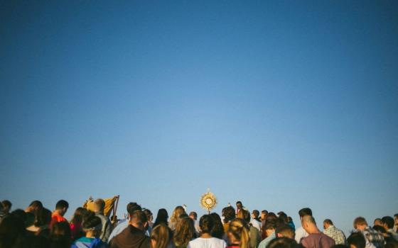 A group of people, including one person carrying a monstrance.