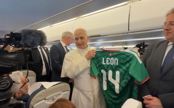 Pope Leo XIV holds a personalized Mexican soccer jersey given to him by Vatican journalist Valentina Alazraki, from Mexico, June 6, on the flight from Rome to Madrid at the start of his visit to Spain. Leo said he hoped the World Cup, which starts June 11, would be a source of unity. (Vatican press pool)
