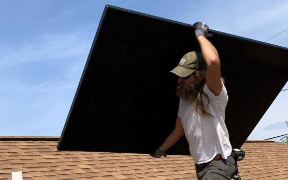 A worker carries a solar panel atop the roof of Mother of Good Counsel Catholic Church, in Hazard, Kentucky. The mission parish completed the solar installation in May. (Lexington Diocese/Joshua Van Cleef)