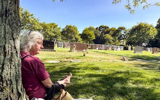 Martha Hennessy, Dorothy Day's granddaughter, sits by her grandmother's grave at Resurrection Cemetery in Staten Island, New York, June 8, 2026. (NCR photo/Camillo Barone)