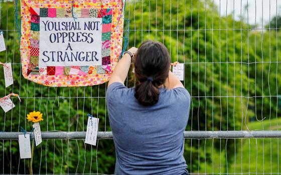 A woman places a message on a fence during a candlelight memorial service at Mechanics Park in Biddeford, Maine, July 13, 2026, after a U.S. Immigration and Customs Enforcement agent fatally shot a motorist. (OSV News/Reuters/CJ Gunther)
