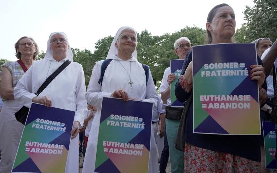 Opponents of "assisted dying" gather during a vote by members of parliament on a bill establishing the right to medical aid in dying at the National Assembly in Paris July 15, 2026. The placards read "Caring = fraternity – Euthanasia = abandonment." (OSV News/Reuters/Noemie Olive)