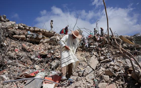 A priest walks through the debris of a collapsed building in La Guaira, Venezuela