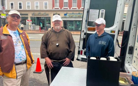 Lay chaplain Gary Riccio (left), Capuchin Franciscan Br. Paul Fesefeldt and a volunteer stand by the Capuchin Mobile Ministries van in Cambridge, Massachusetts, in mid-June. "It's like a mobile coffee hour," said Fesefeldt, founder and director of the ministry. (Greta Gaffin)