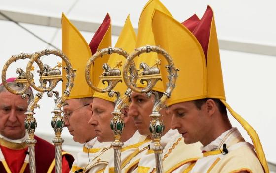 Newly consecrated bishops, from left, Pascal Schreiber, Michael Goldade, Michel Poinsinet de Sivry and Marc Hanappier, wearing their miters and holding their pastoral staffs, pray at the end of their consecration ceremony in a tent set up outside the Society of St. Pius X seminary in Écône, Switzerland, July 1, 2026. (AP/Baz Ratner)