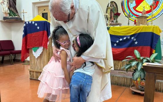 Missionary priest Fr. Raymond Riding hugs two little girls at a Mass hastily organized on June 27 in Tucson, Arizona, to support Venezuelan migrants who are worried and in mourning after two devastating earthquakes killed hundreds of people and injured thousands more in their homeland on June 24. (Anita Snow)