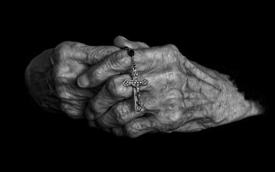 hands clasped and holding small cross/rosary