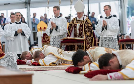 Four bishops lie on the floor as they are given episcopal consecration during a Mass in a tent set up outside the Society of St. Pius X seminary, in Econe, Switzerland, July 1, 2026. (Cyril Zingaro/Keystone via AP)
