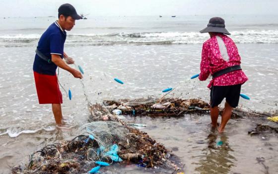 Workers remove trash from a clam-farming area in Vinh An, Vietnam, on June 17, 2026. Farmers say plastic waste and other flood-borne debris have contributed to declining harvests. (Joachim Pham)