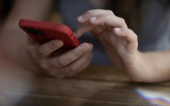 Hands holding and tapping on a cellphone (Unsplash/Rapha Wilde)